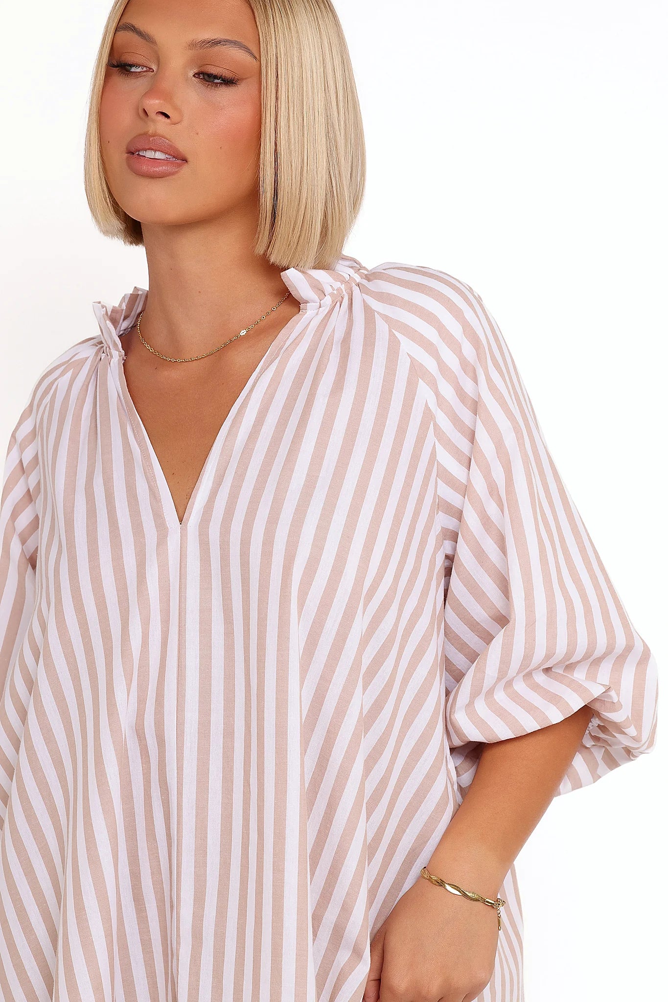 Side view showing the drape of the beige & white stripe mini dress