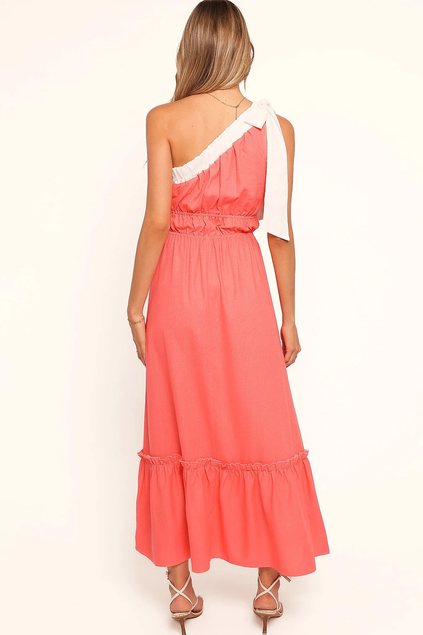 Side view showing the drape of the coral one-shoulder maxi dress
