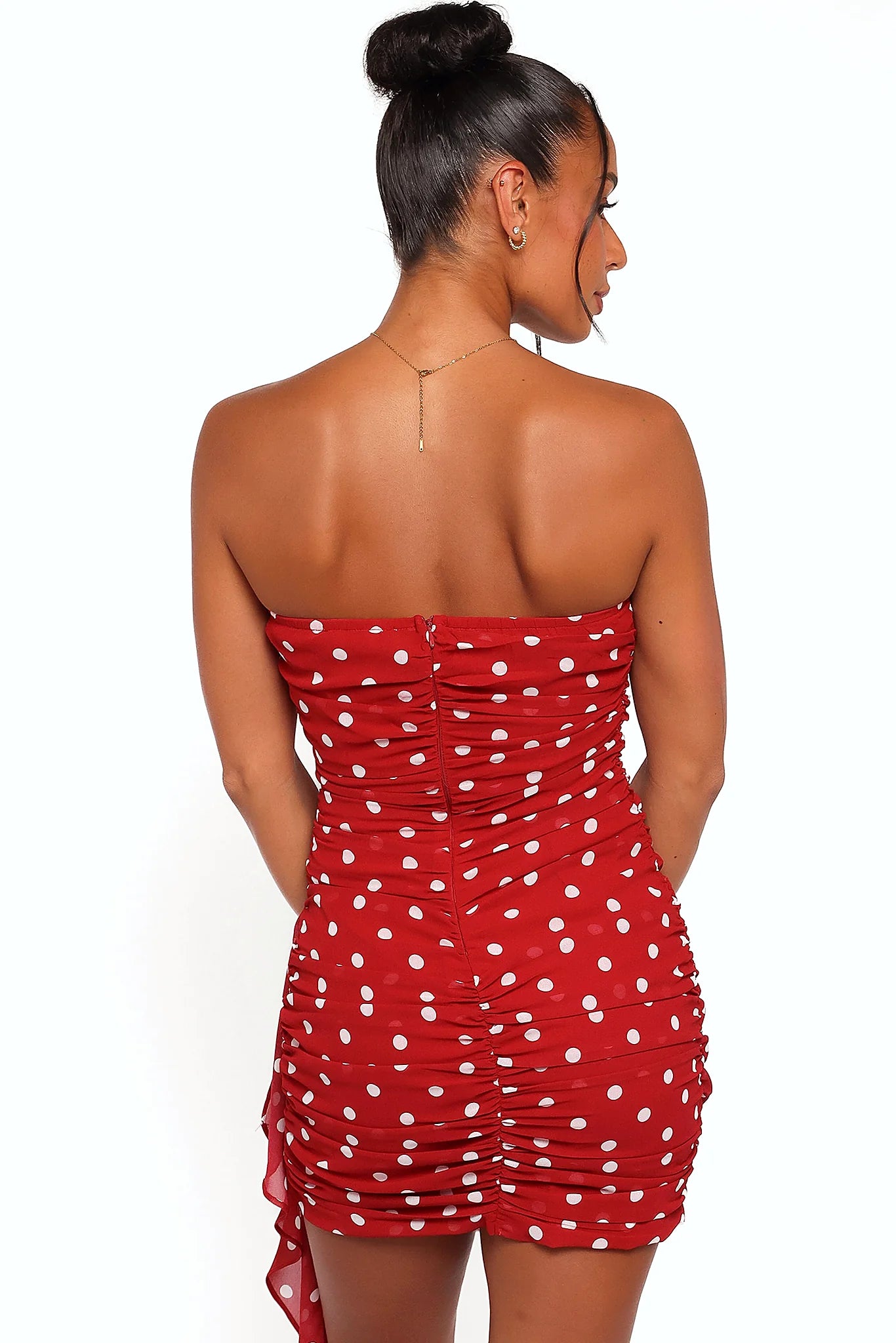 Back view of the red polka dot strapless mini dress on a model