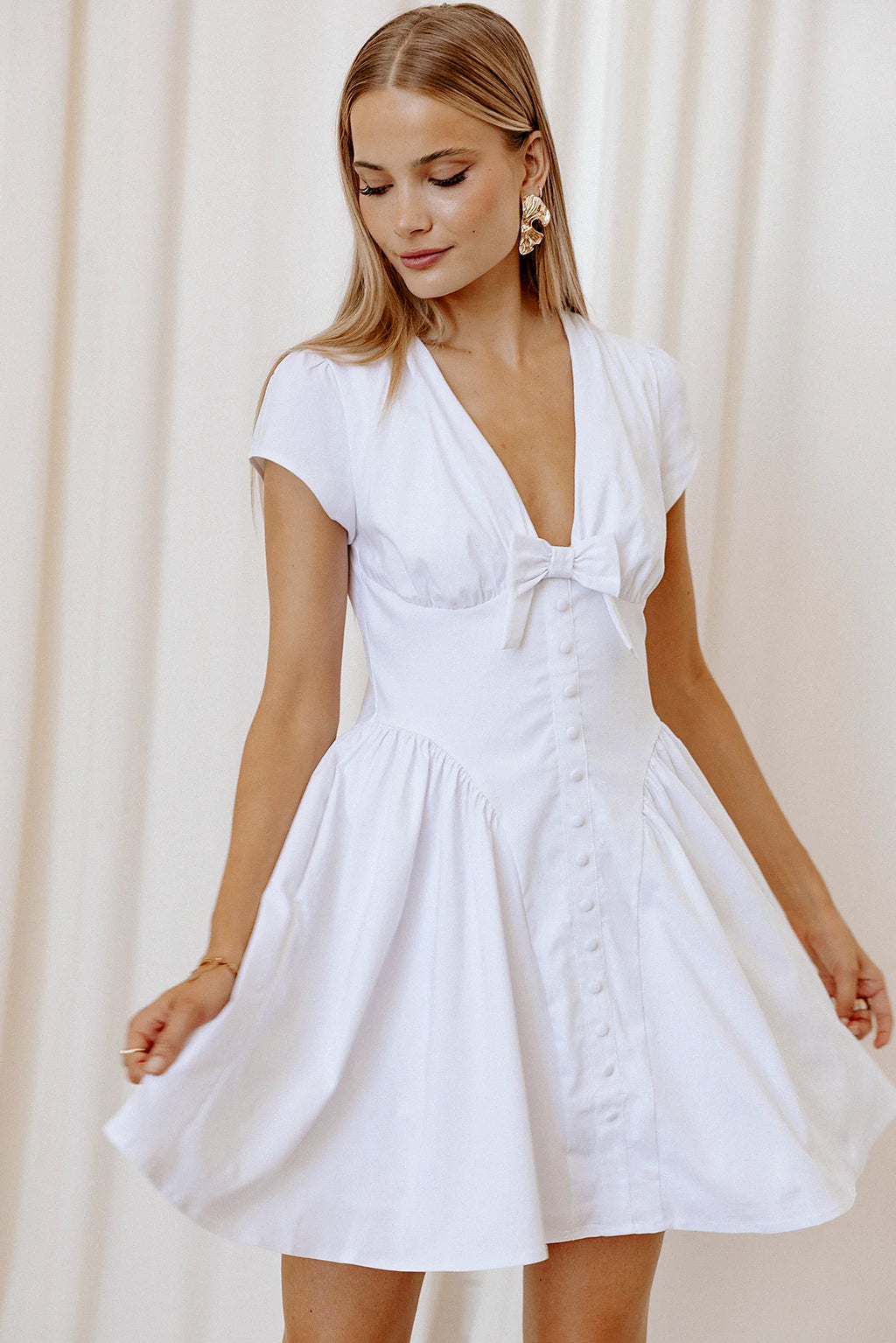 Model wearing the white bow-front mini dress, front view
