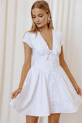 Model wearing the white bow-front mini dress, front view