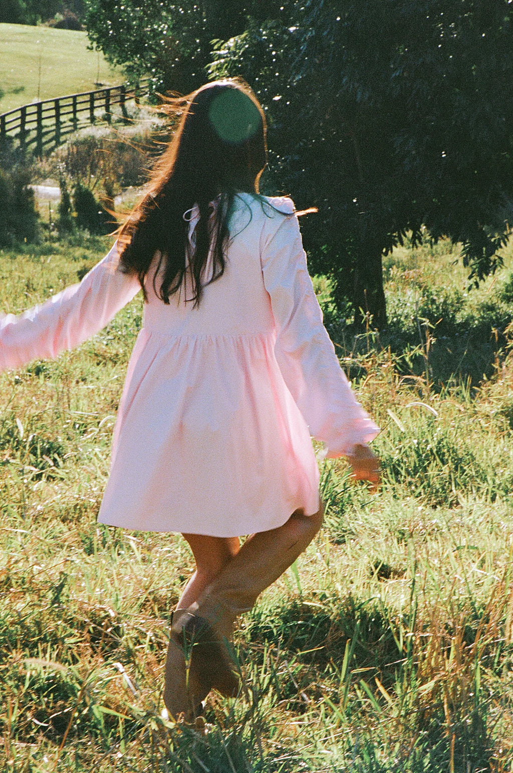 Side view showing the drape of the pink smock long sleeve mini dress