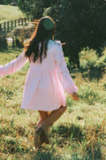 Side view showing the drape of the pink smock long sleeve mini dress