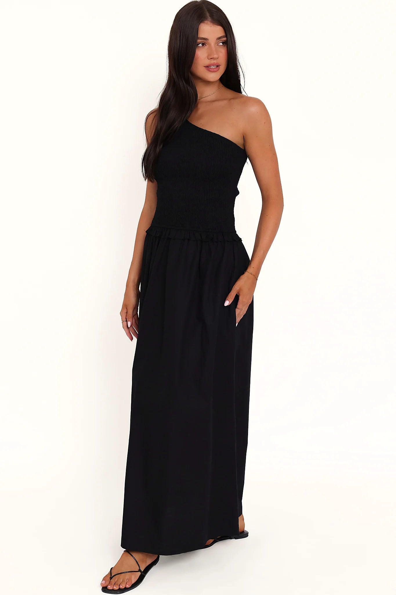 Side view showing the drape of the black one-shoulder maxi dress