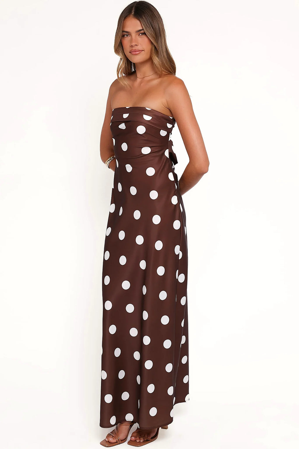 Side view showing the drape of the brown polka dot strapless maxi dress