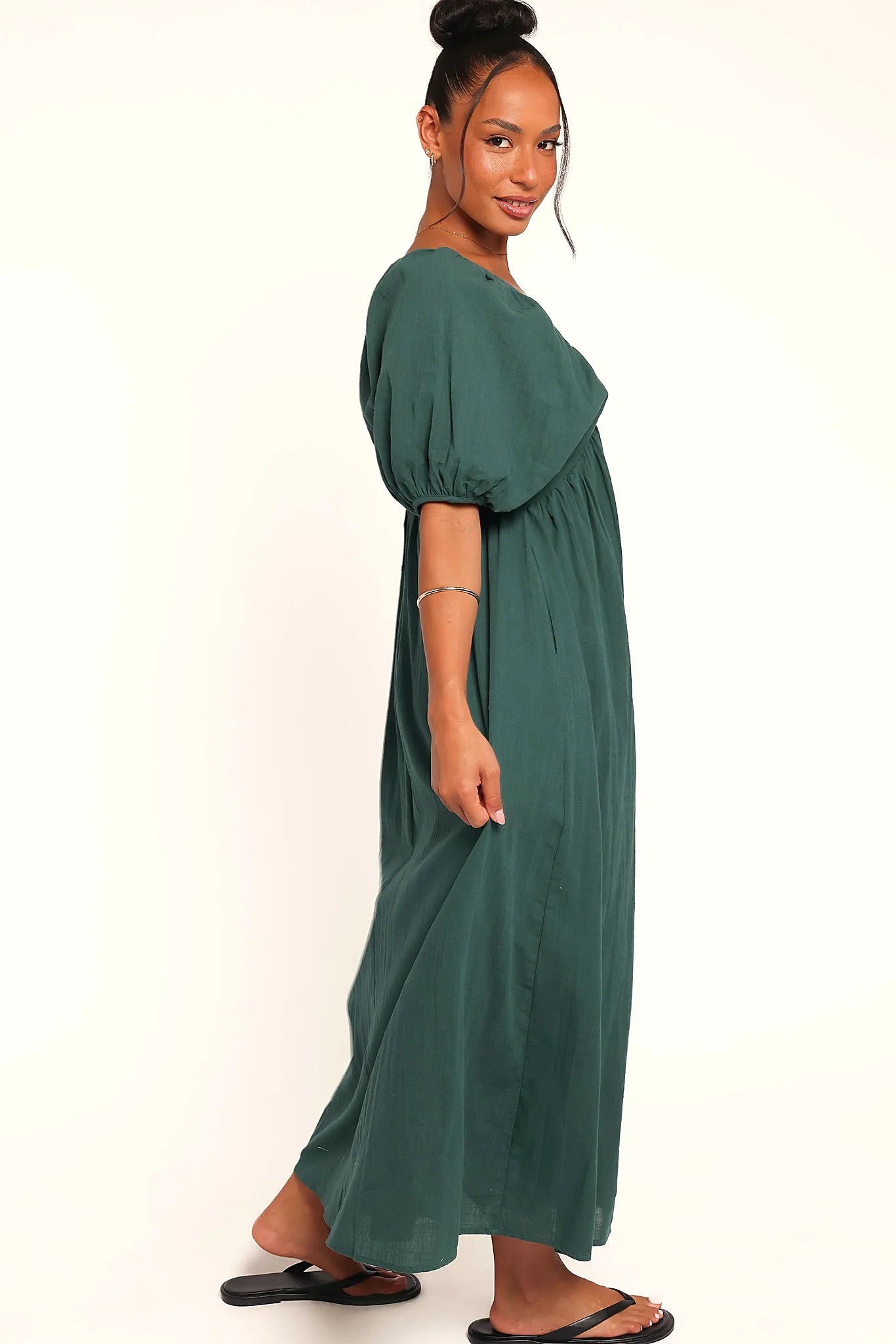 Side view showing the drape of the forest green puff-sleeve maxi dress